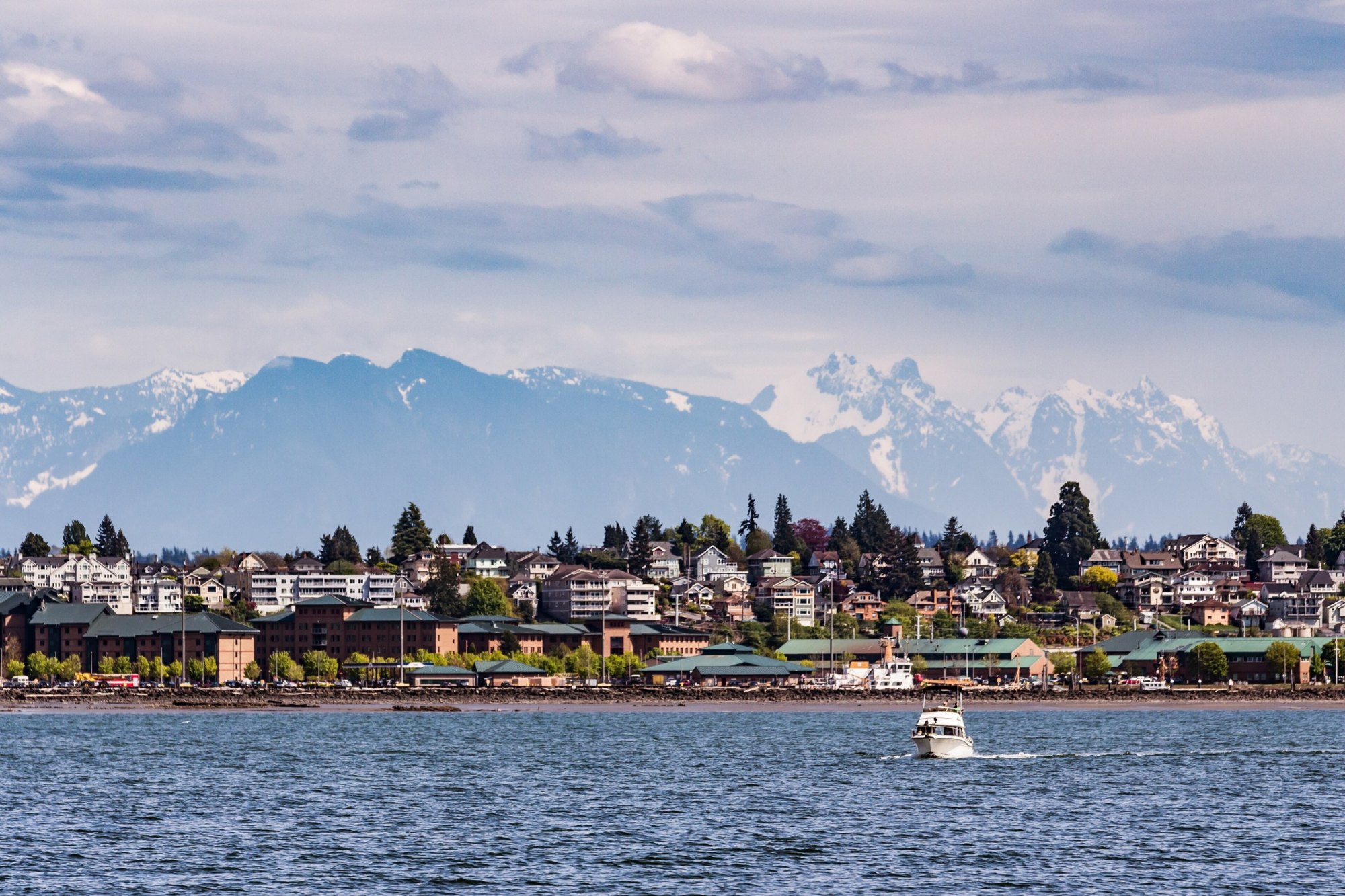 Hillside homes of Everett along the waterfront, with snow-capped Cascade peaks and a passing boat