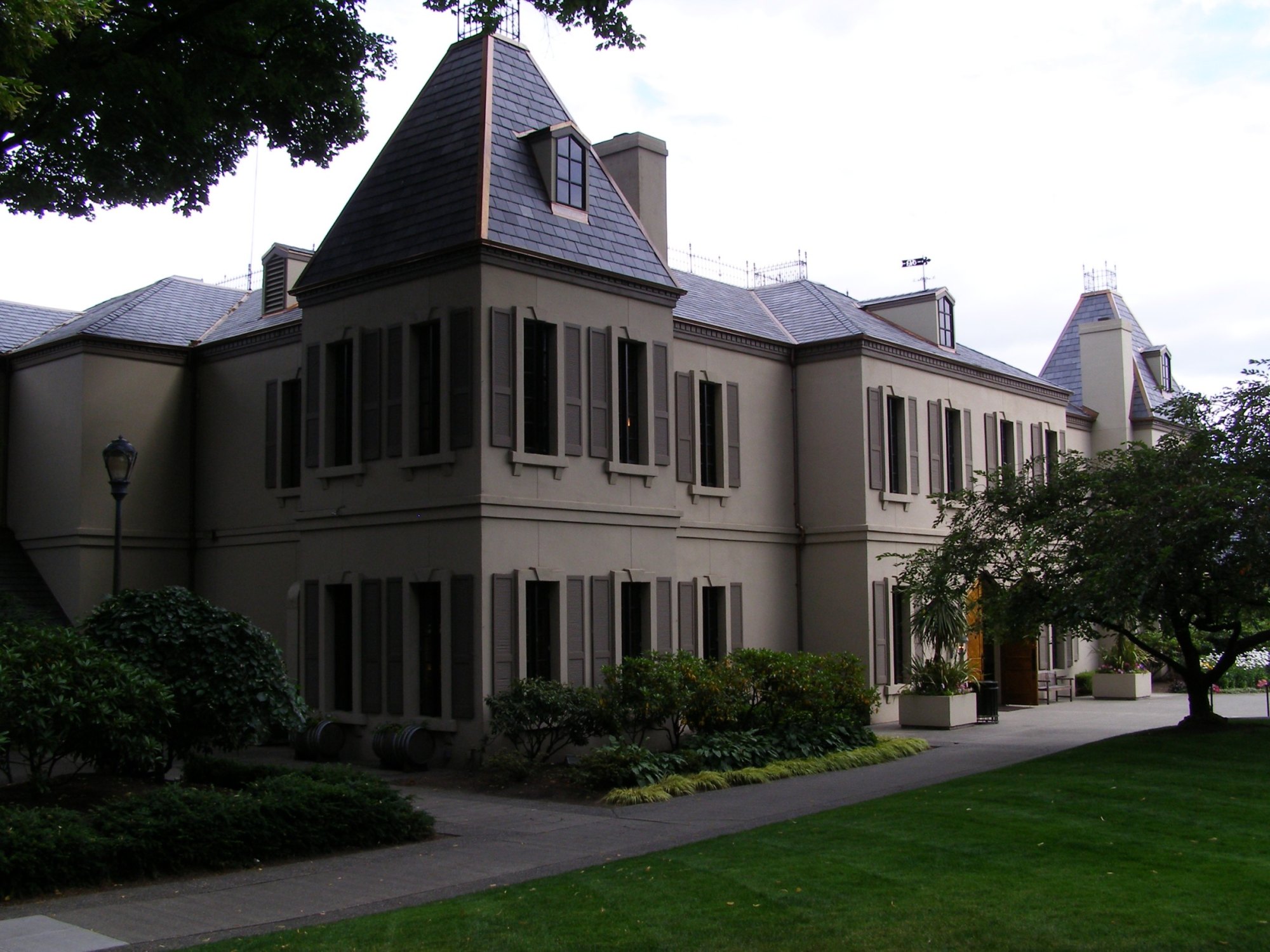 French chateau-style winery building with slate turrets, shuttered windows and a manicured lawn