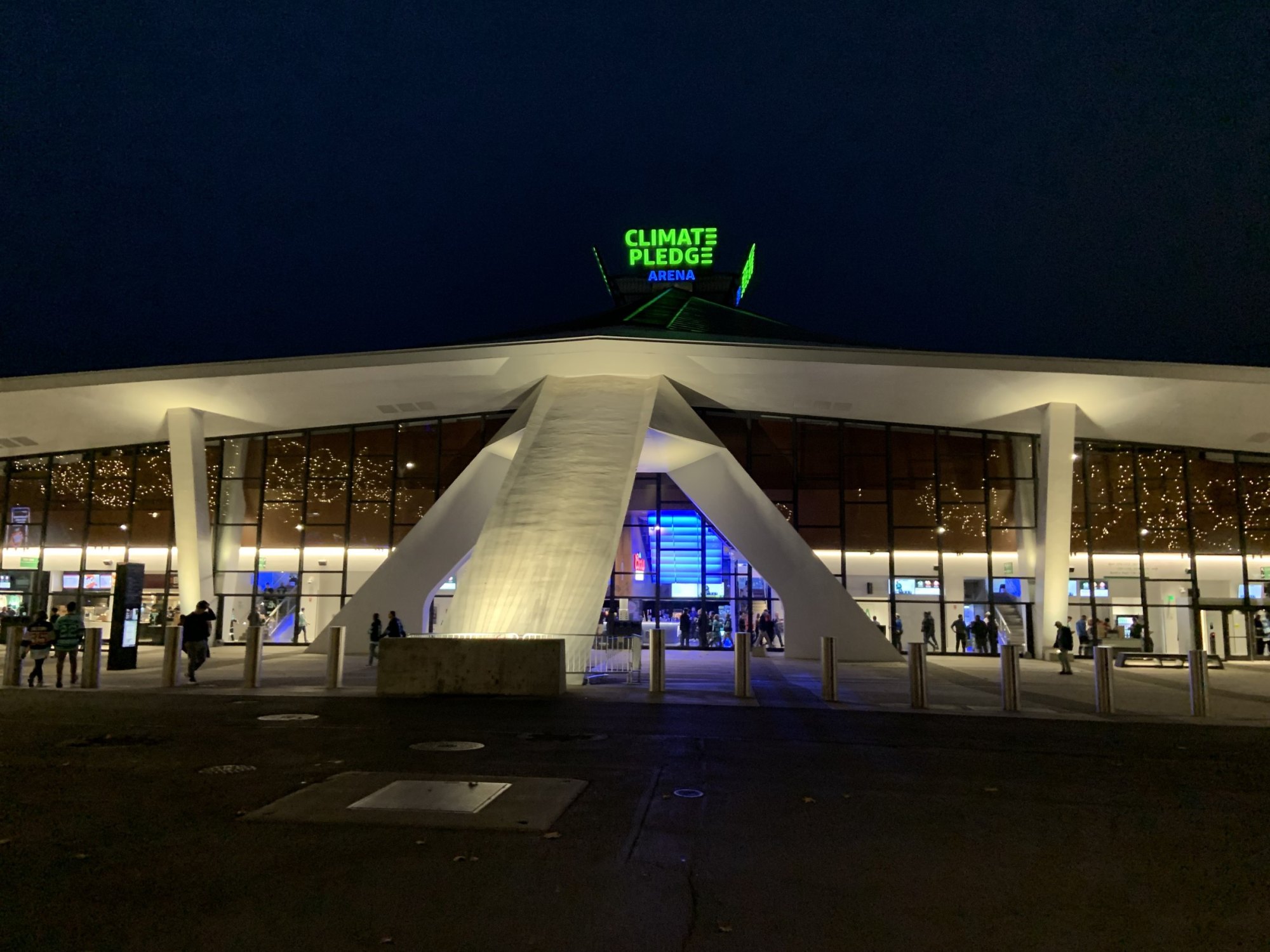 Climate Pledge Arena entrance lit up at night with glowing sign and glass facade