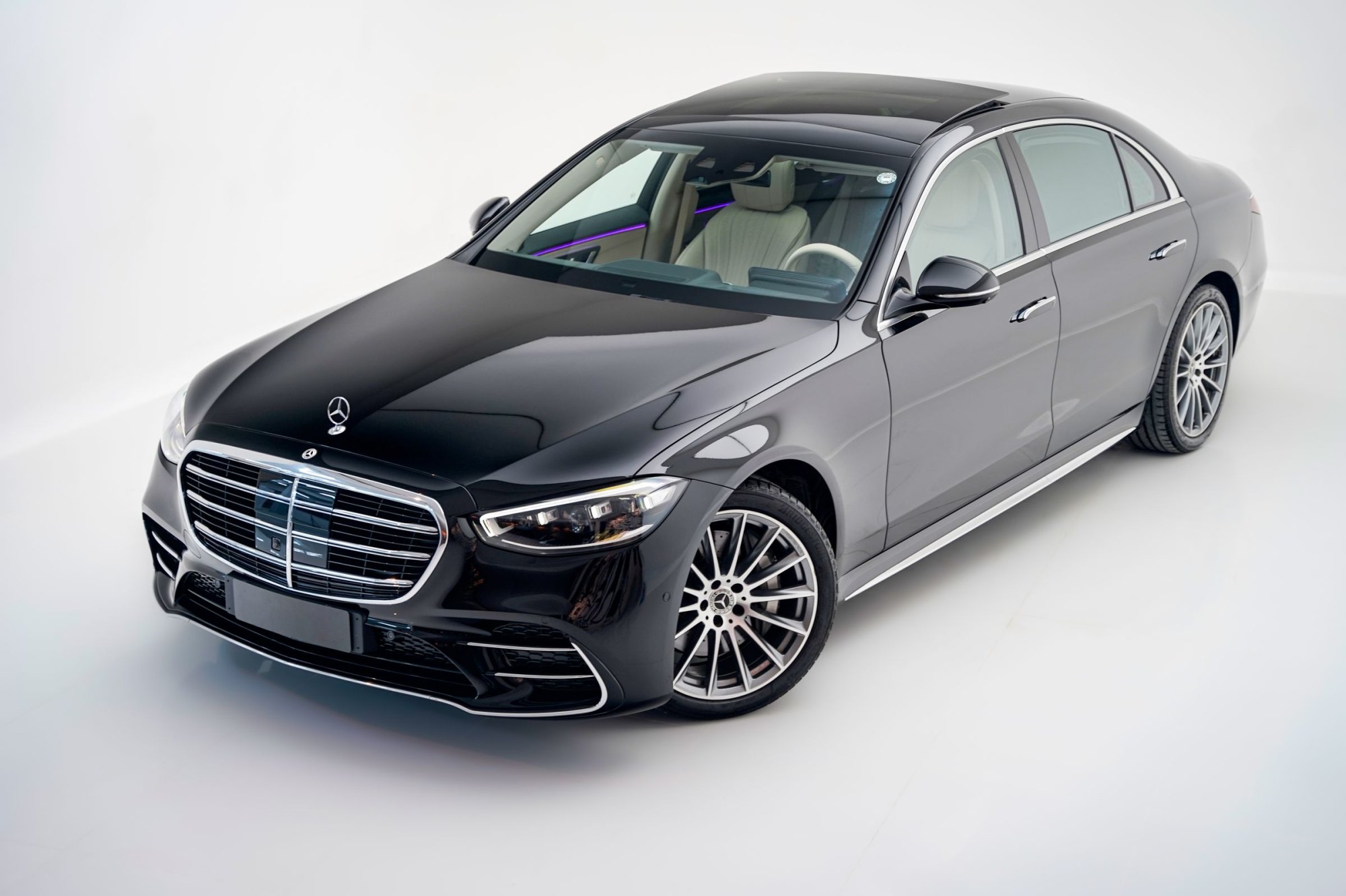 Black full-size luxury sedan photographed from a high front angle in a white studio